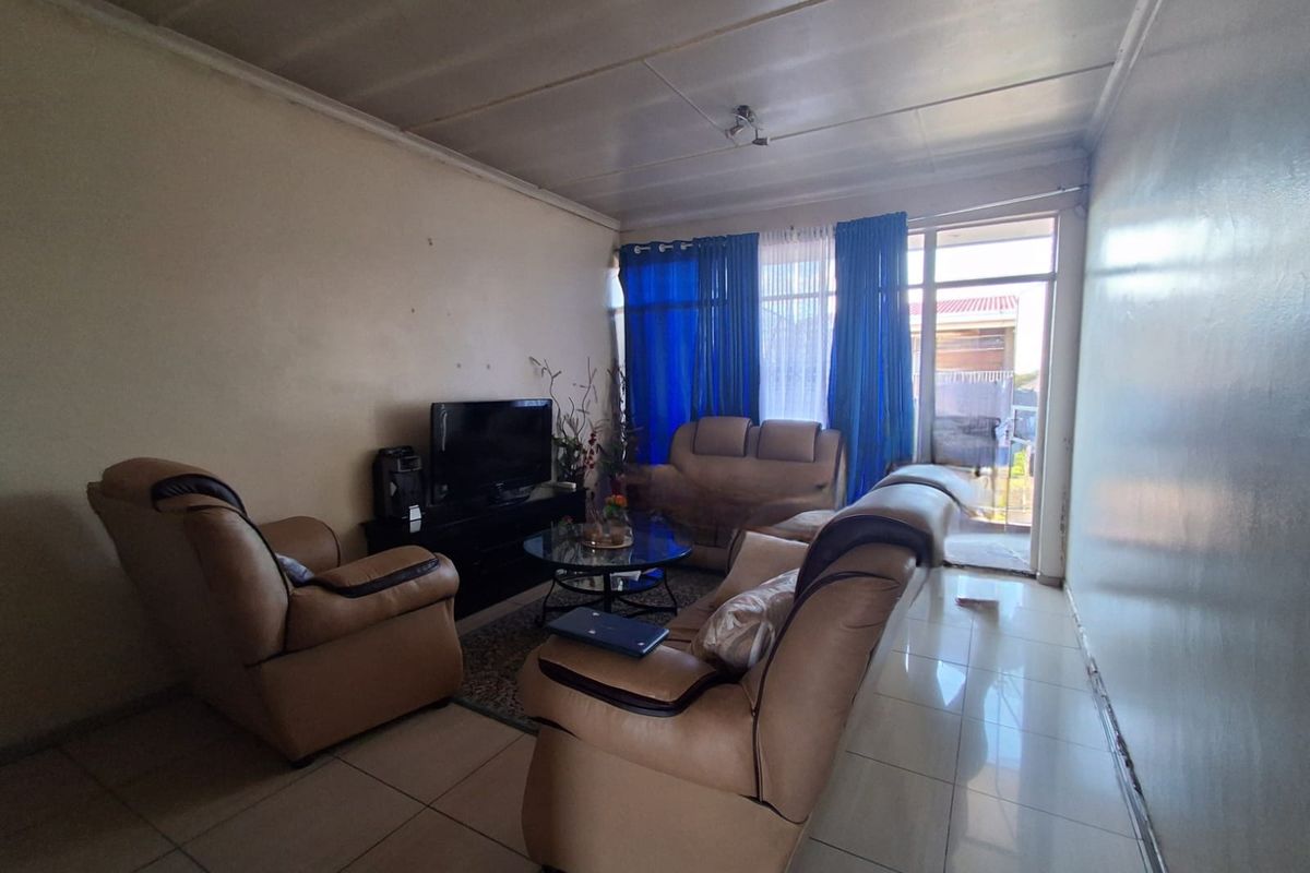 A living room featuring tiled flooring and direct access to an outdoor area through a glass door.