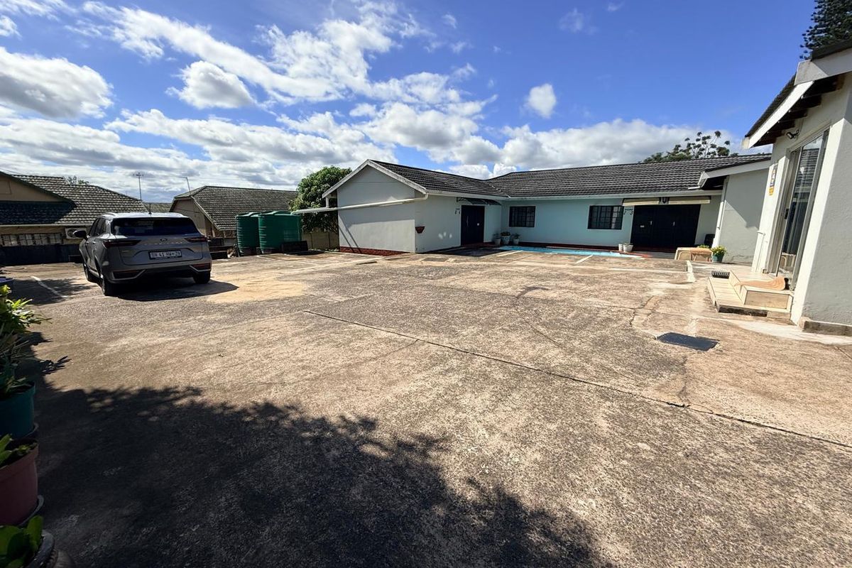 Spacious exterior courtyard area featuring extensive concrete paving, water storage tanks, and access to the main guest house structure.