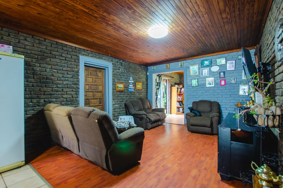 A living room featuring exposed brick walls, a timber-paneled ceiling, and wood-look flooring, providing a rustic and cozy atmosphere.