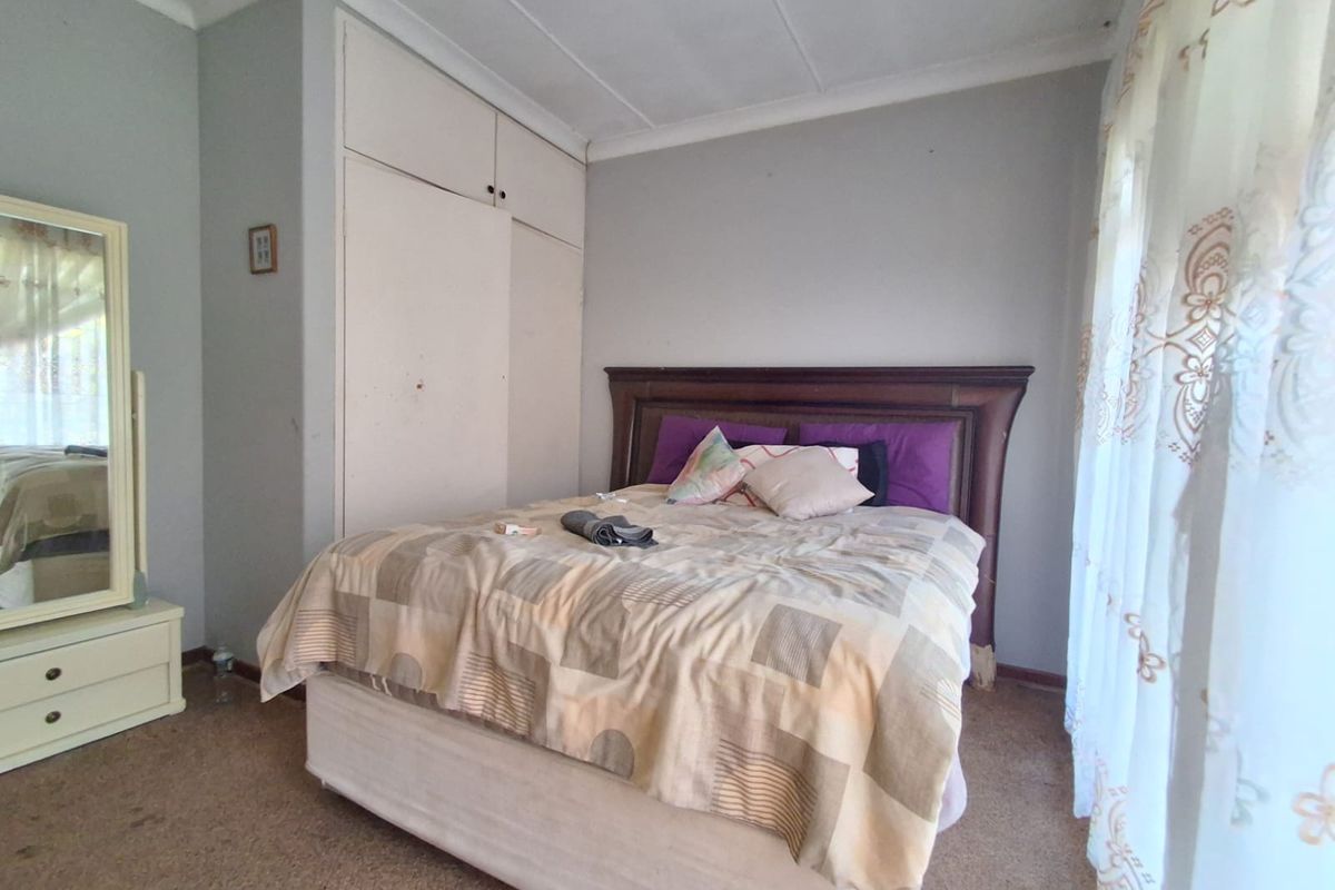 A bedroom featuring built-in wardrobes, carpeted flooring, and a window with curtains, offering a functional space ready for updates.