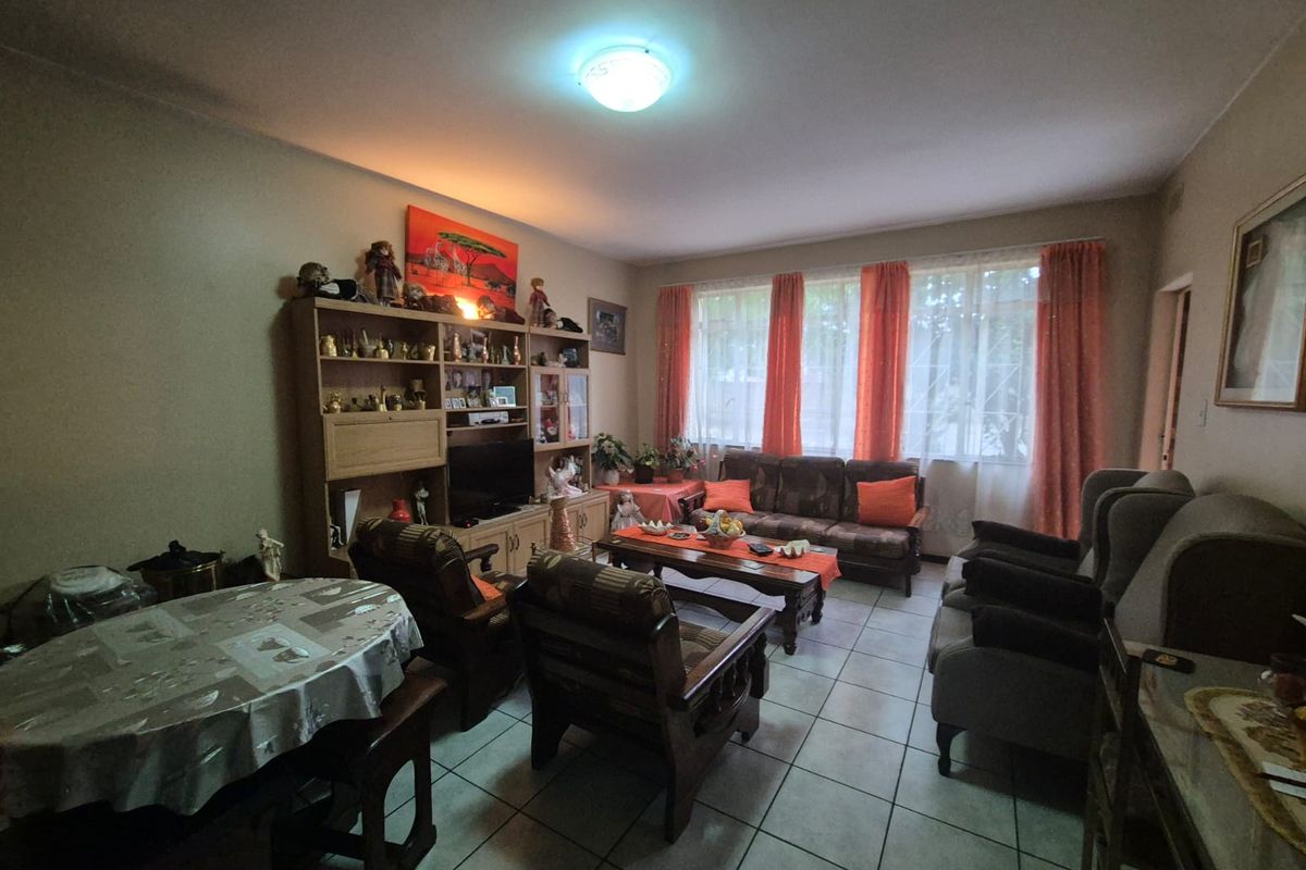 A spacious living room featuring tiled flooring and large windows that allow for natural light, providing a comfortable and functional living area.