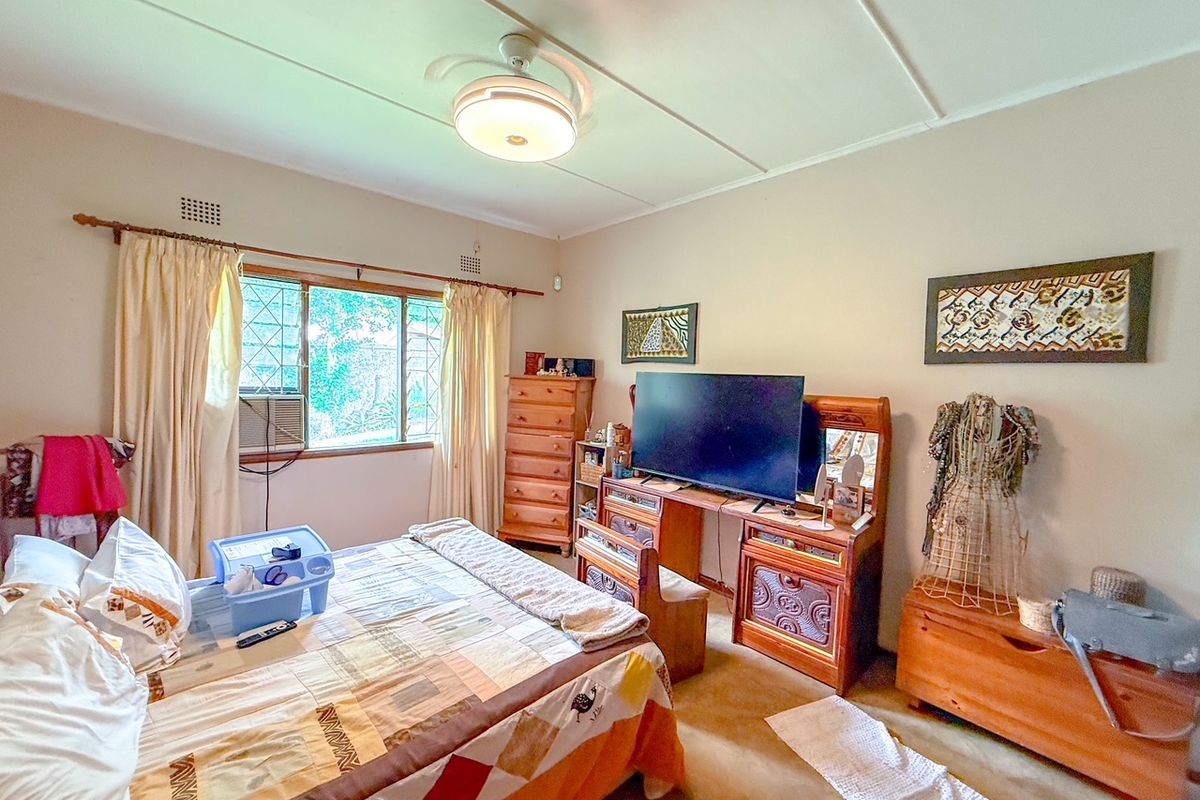 A bedroom featuring a ceiling fan, built-in window security bars, and a wall-mounted air conditioning unit.