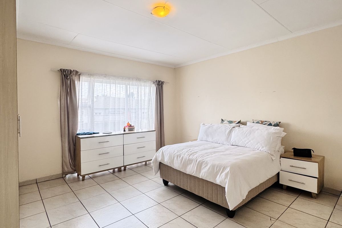 A spacious bedroom featuring neutral tiled flooring, built-in cabinetry, and large windows allowing for natural light.