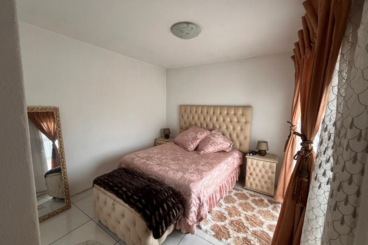 A well-maintained bedroom featuring tiled flooring and neutral wall finishes, providing a comfortable and functional living space.