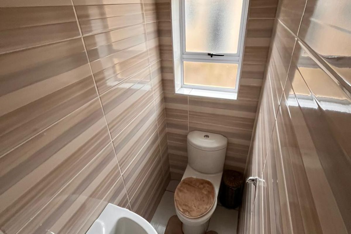 A compact guest bathroom featuring floor-to-ceiling striped wall tiles, a pedestal basin, and a standard toilet.