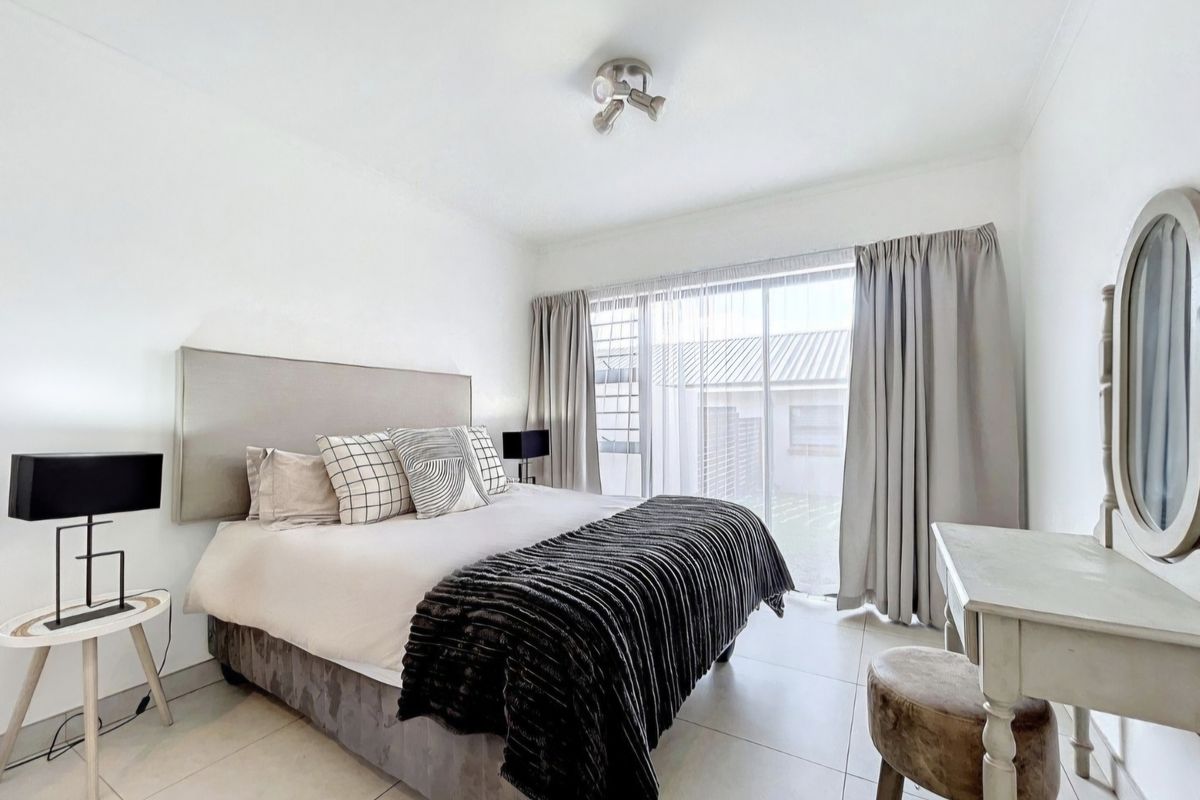A bright and well-maintained bedroom featuring large sliding glass doors that provide natural light and access to the exterior.