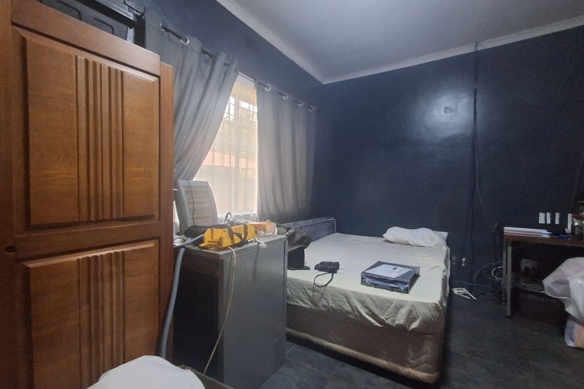 A bedroom featuring dark-painted walls, tiled flooring, and a window with curtain treatments.