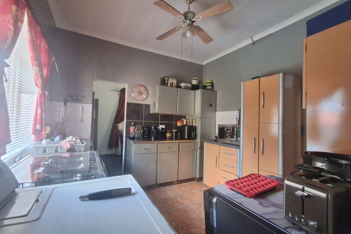 A functional kitchen featuring built-in cabinetry, tiled flooring, a ceiling fan, and tiled splashbacks, offering a practical layout for daily meal preparation.