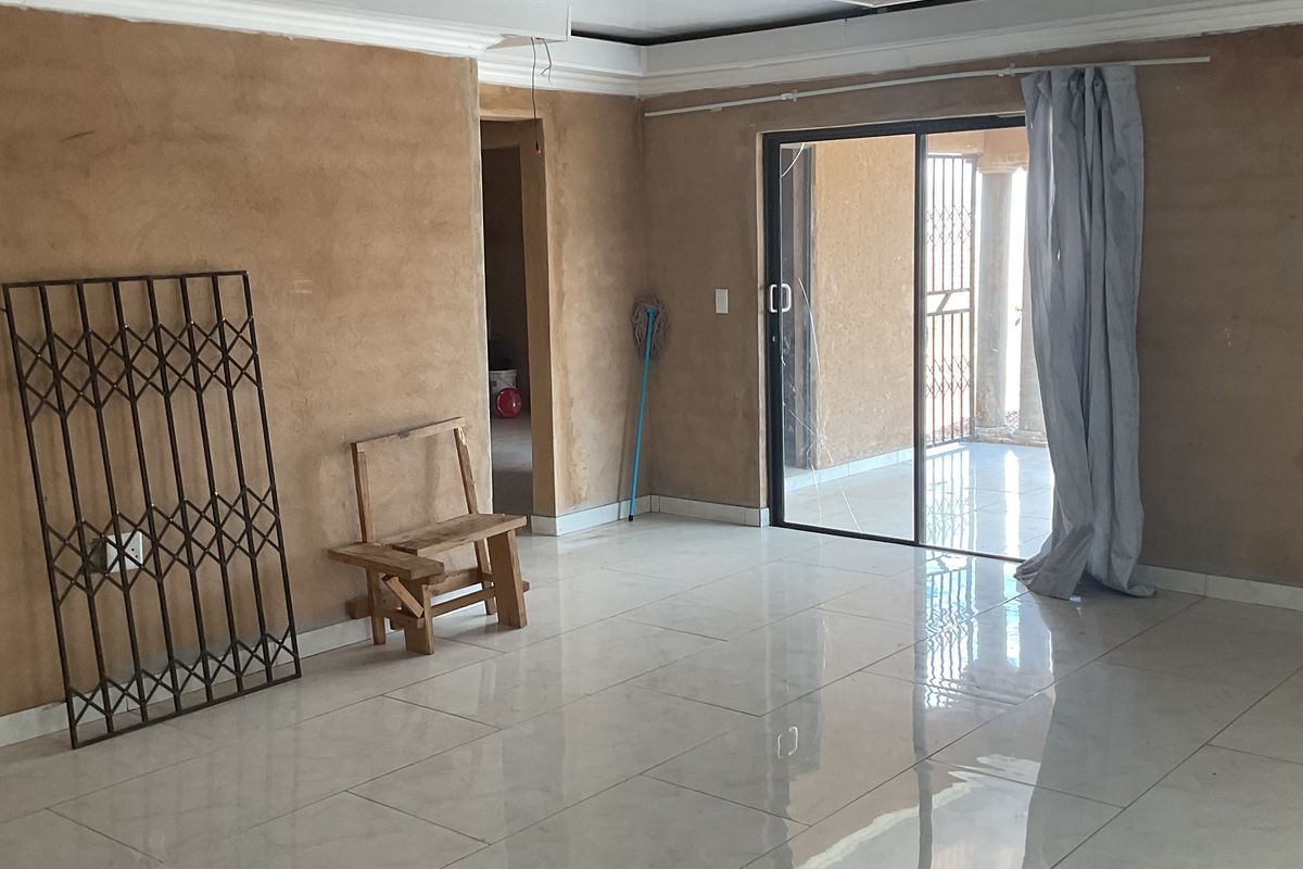 Spacious living area featuring polished porcelain floor tiles, recessed ceiling lighting, and sliding glass doors leading to an outdoor patio.