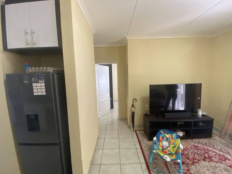 A view of the living area featuring tiled flooring, neutral wall paint, and a built-in overhead kitchen cabinet.