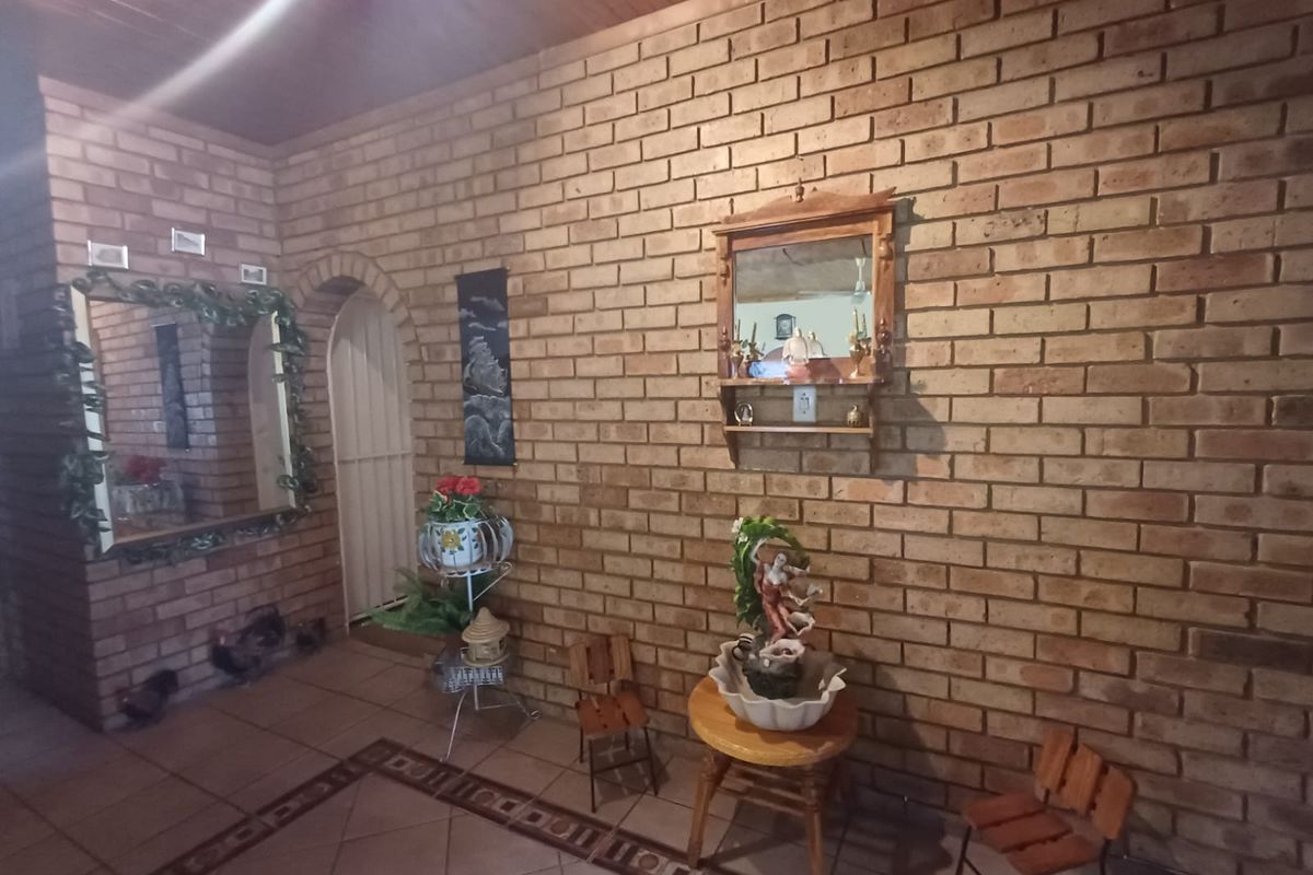 An interior living space featuring exposed face-brick walls, tiled flooring with decorative borders, and a timber-paneled ceiling with an arched doorway.