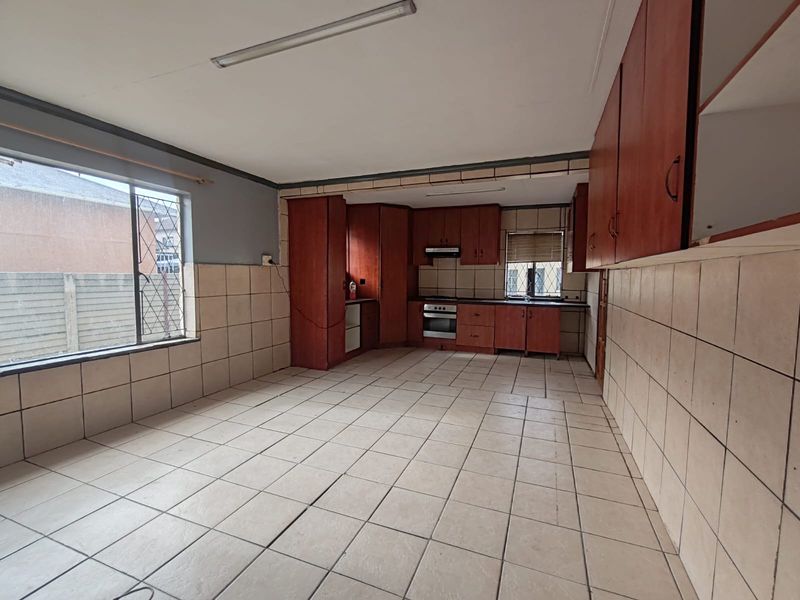 Spacious kitchen featuring tiled walls and floors, built-in cabinetry, and integrated oven with extractor fan, offering a blank canvas for renovation.