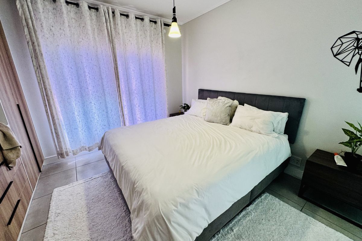 A well-maintained bedroom featuring tiled flooring, a built-in wardrobe, and a sliding door providing access to natural light.