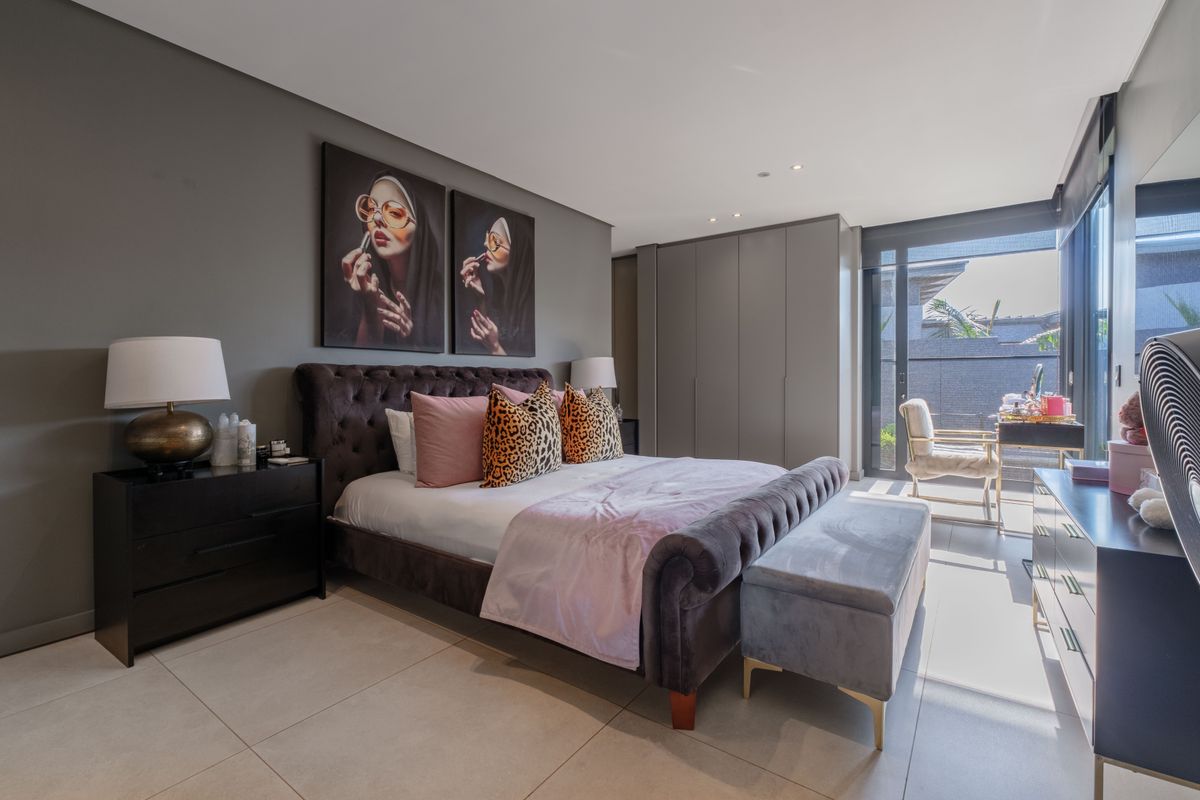 Modern bedroom featuring large format floor tiles, built-in floor-to-ceiling wardrobes, and sliding glass doors leading to a private balcony.