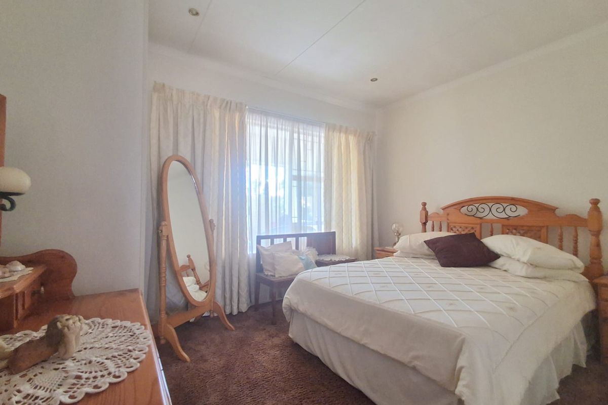 A bedroom featuring carpeted flooring, recessed ceiling lighting, and a large window with curtain tracks.