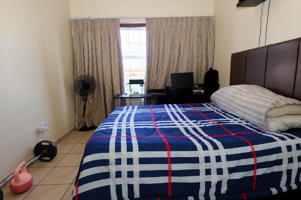 A bedroom featuring tiled flooring and a window with curtains, providing a functional space for rest.