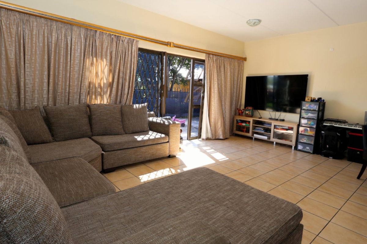 Spacious living room featuring ceramic floor tiles and sliding glass doors with security gates, providing direct access to the outdoor patio area.