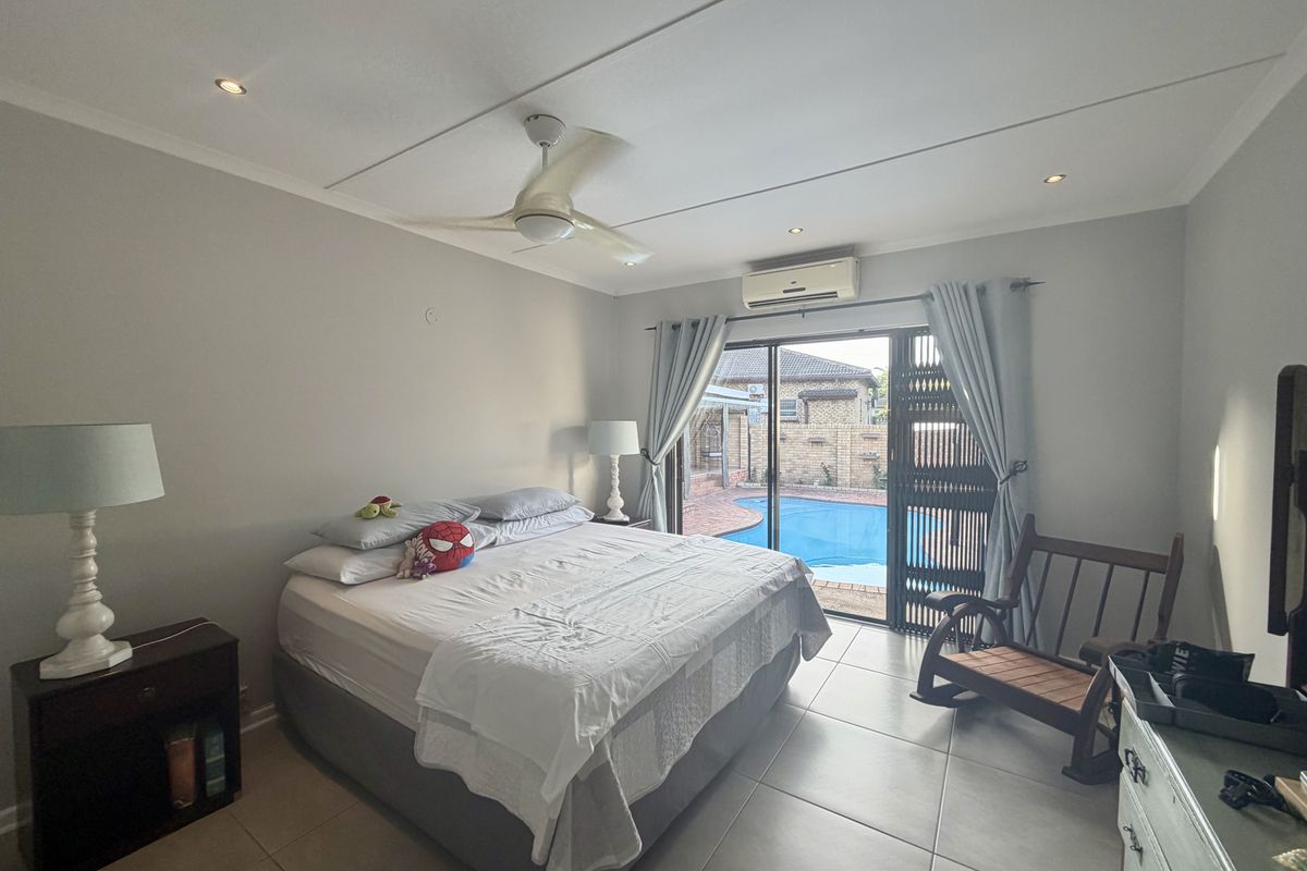 A well-maintained bedroom featuring tiled flooring, a ceiling fan, and sliding glass doors that open directly to a private swimming pool area.