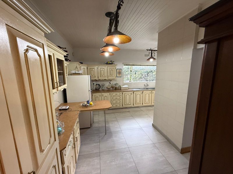 A functional kitchen featuring traditional cabinetry, tiled flooring, and a breakfast bar area with pendant lighting.
