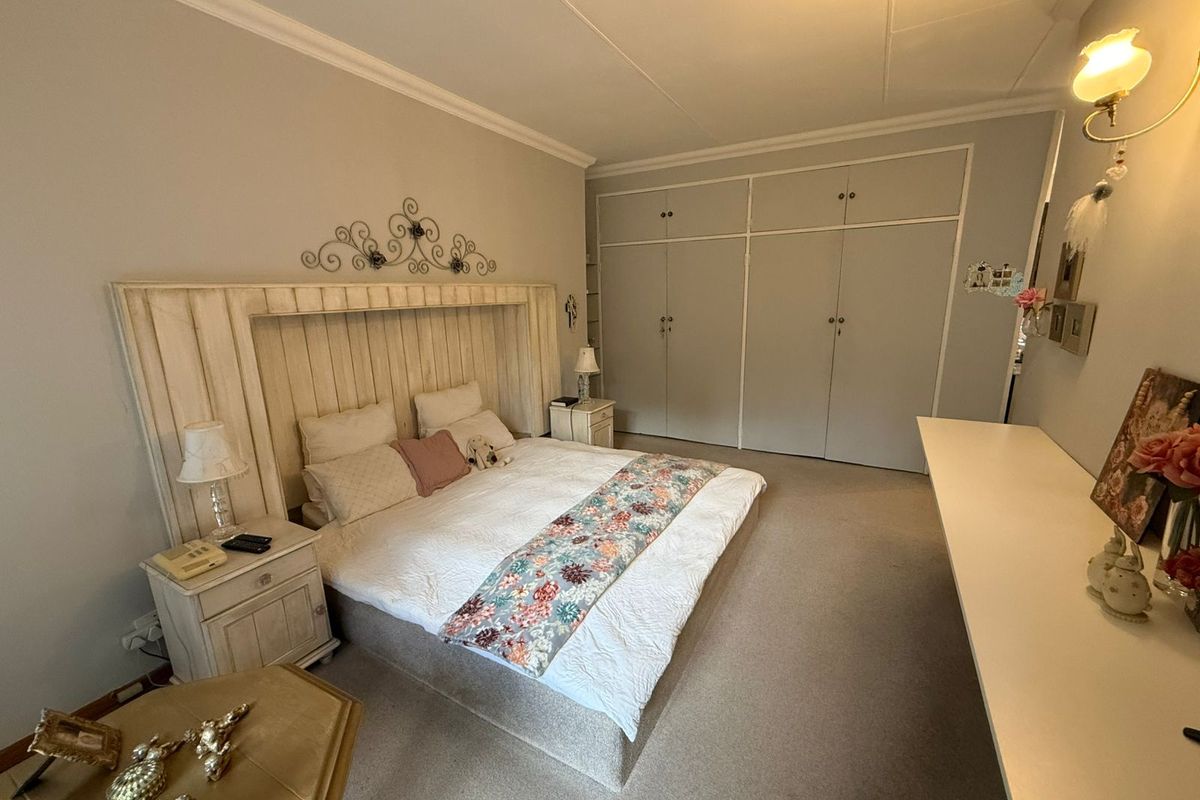 Spacious bedroom featuring extensive built-in wardrobe storage, neutral wall finishes, and carpeted flooring.