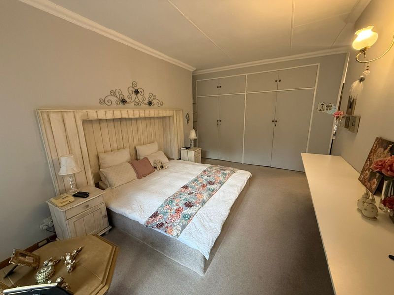 Spacious bedroom featuring extensive built-in wardrobe storage, neutral wall finishes, and carpeted flooring.