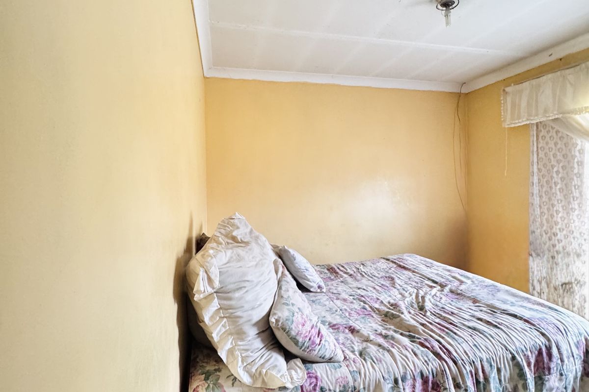 A bedroom featuring yellow painted walls and a tiled ceiling, providing a functional space for rest.