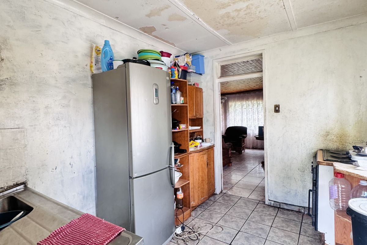 A dated kitchen area featuring tiled flooring and built-in cabinetry, requiring significant renovation and cosmetic updates to restore the space.