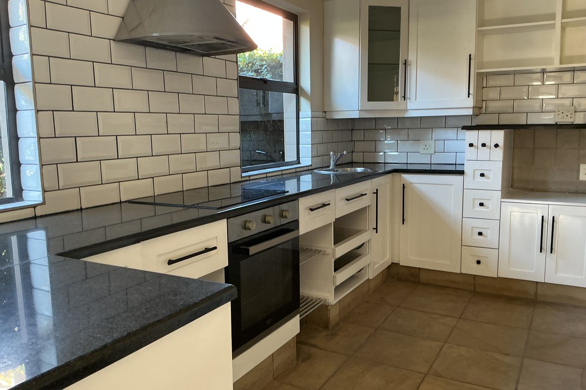 A functional kitchen featuring white cabinetry, dark granite countertops, subway tile backsplash, built-in oven, and stainless steel extractor fan.