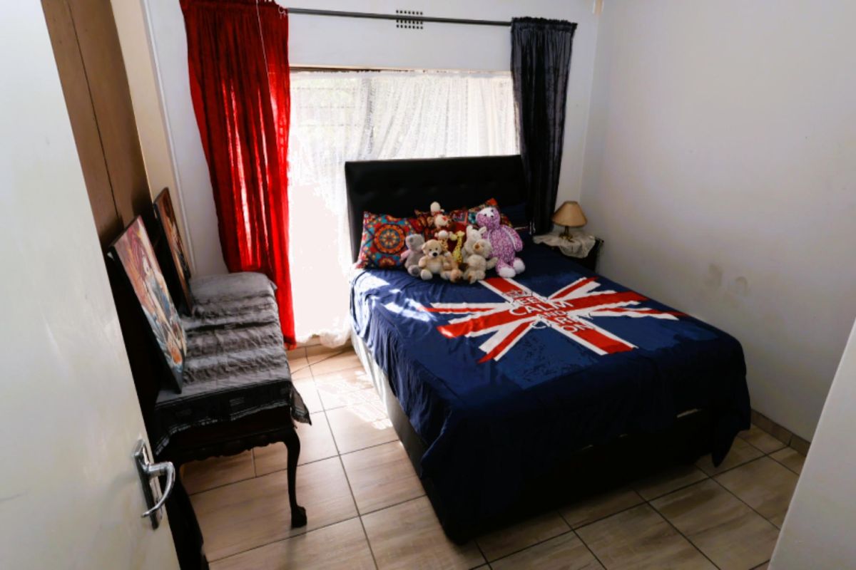 A standard bedroom featuring tiled flooring and a window with curtain tracks.