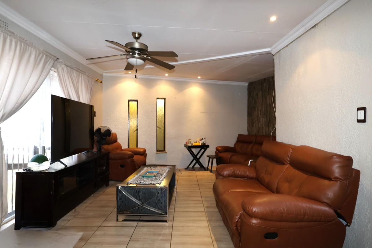 A comfortable living room featuring tiled flooring, recessed ceiling lighting, a central ceiling fan, and decorative vertical wall niches.