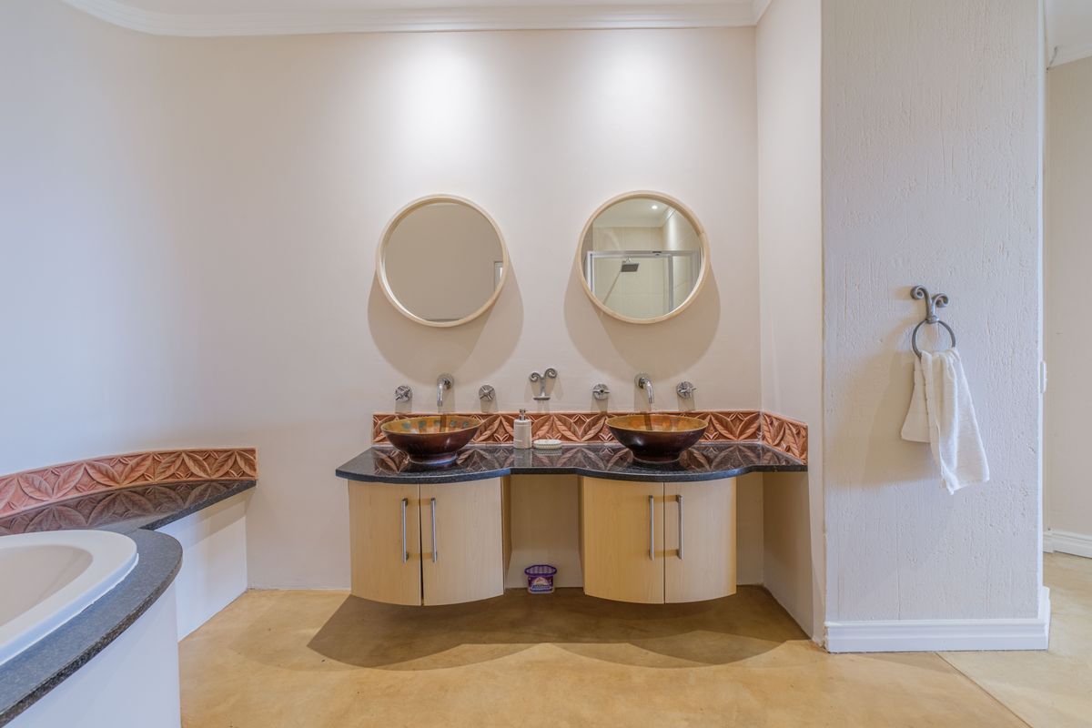 A bathroom featuring a double vanity with vessel sinks, granite countertops, and circular mirrors, complemented by a built-in bathtub with matching granite surround.