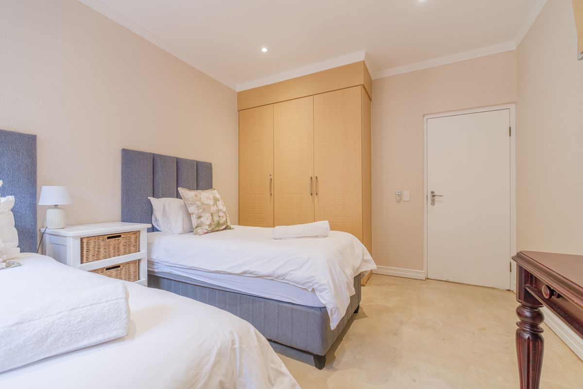 A well-maintained bedroom featuring built-in wooden cupboards, recessed ceiling lighting, and neutral wall finishes.