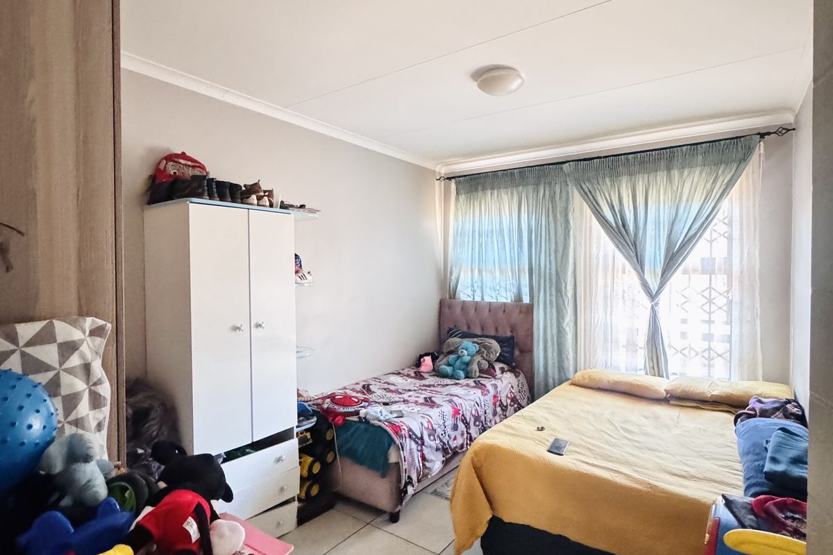 A bedroom featuring tiled flooring, built-in cabinetry, and a window with curtain treatments.