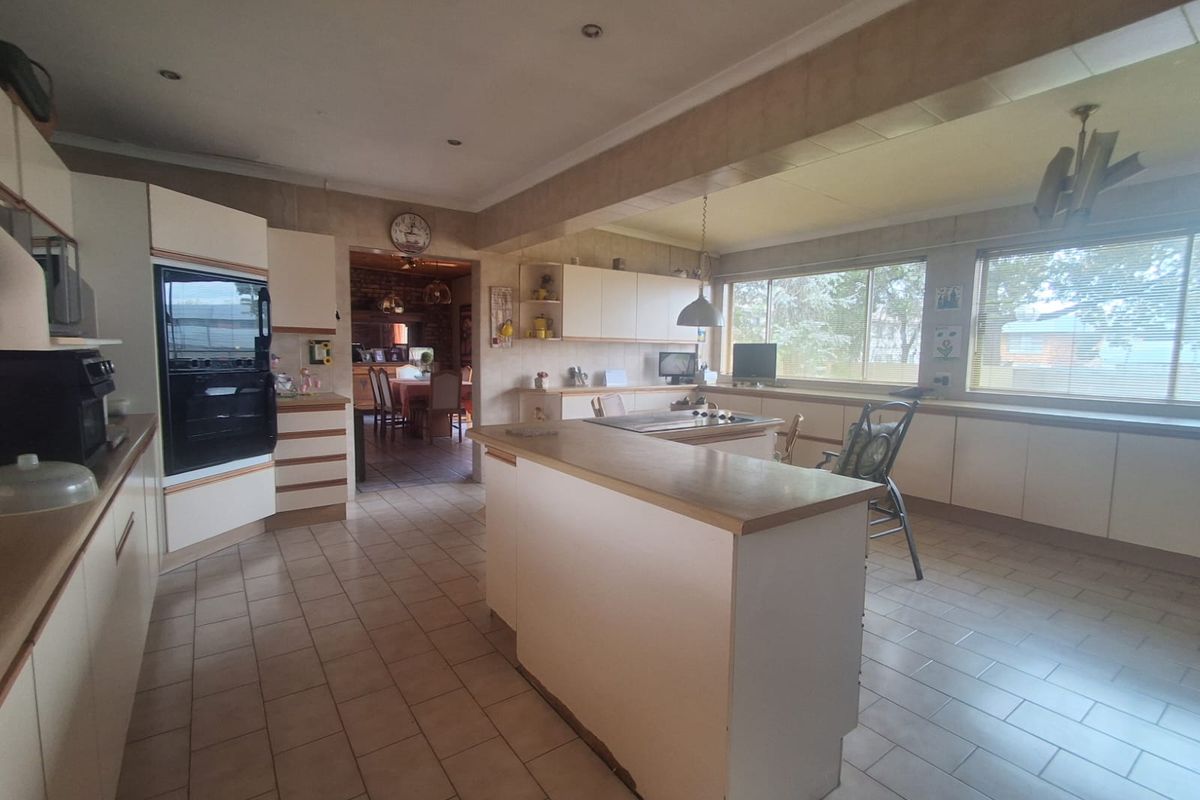 Spacious kitchen featuring a central island, built-in oven, ample cabinetry, and large windows providing natural light, with an open flow to the dining area.
