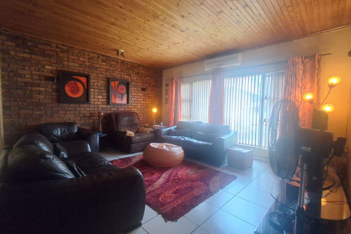 A living room featuring a prominent exposed brick feature wall, timber-clad ceiling, and a wall-mounted air conditioning unit.