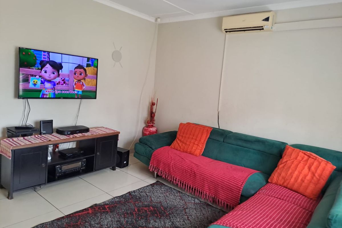 A functional living room featuring tiled flooring and a wall-mounted air conditioning unit.