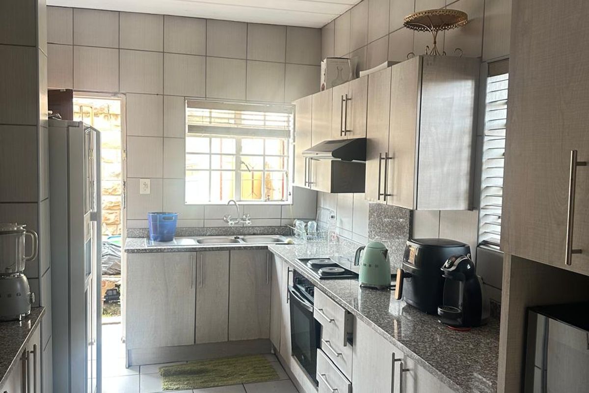 A functional kitchen featuring light wood-finish cabinetry, granite countertops, a built-in oven, and a stainless steel sink with direct access to the exterior.