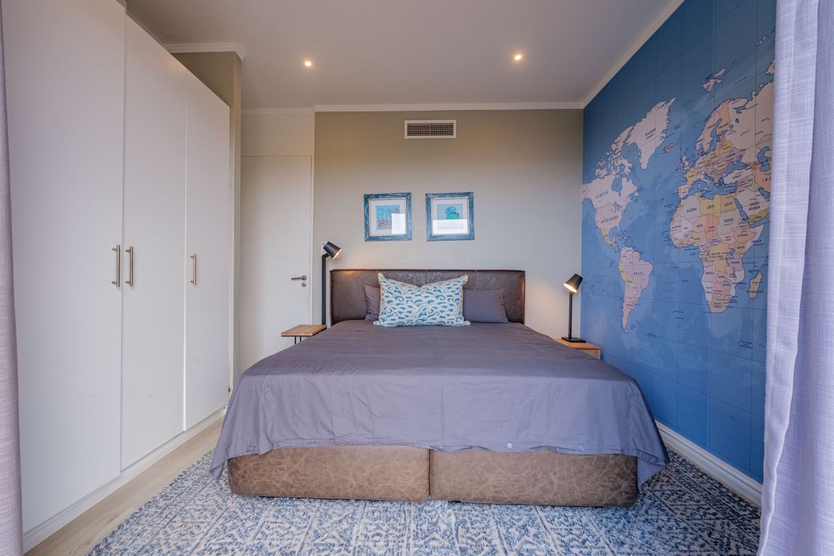 A well-maintained bedroom featuring built-in floor-to-ceiling wardrobes, recessed downlighting, and integrated air conditioning vent.