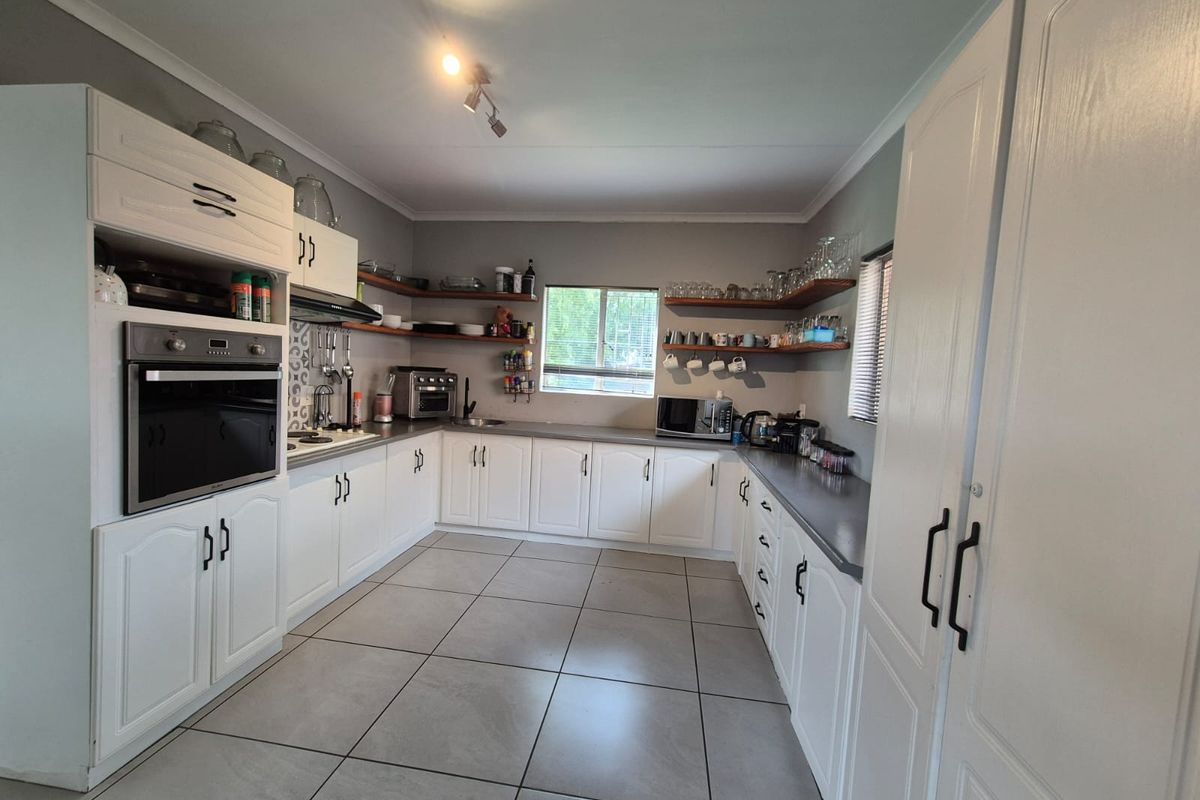 A well-maintained kitchen featuring white cabinetry, built-in oven, tiled flooring, and open shelving, providing a functional and bright workspace.
