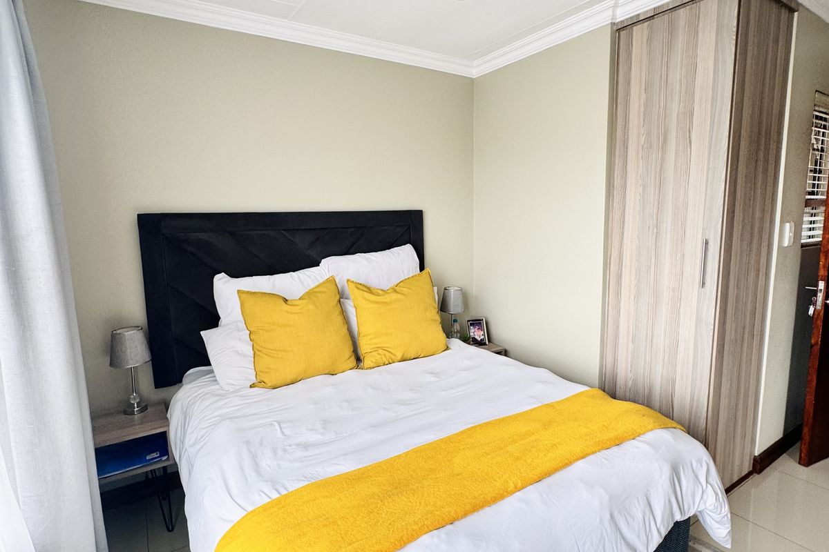 A well-maintained bedroom featuring built-in cabinetry, tiled flooring, and crown molding, offering a clean and functional living space.
