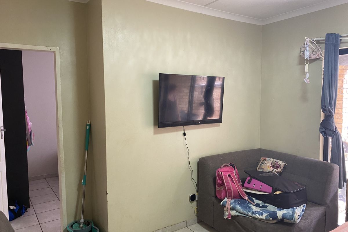 A living room area featuring tiled flooring, coved ceilings, and a wall-mounted television point.