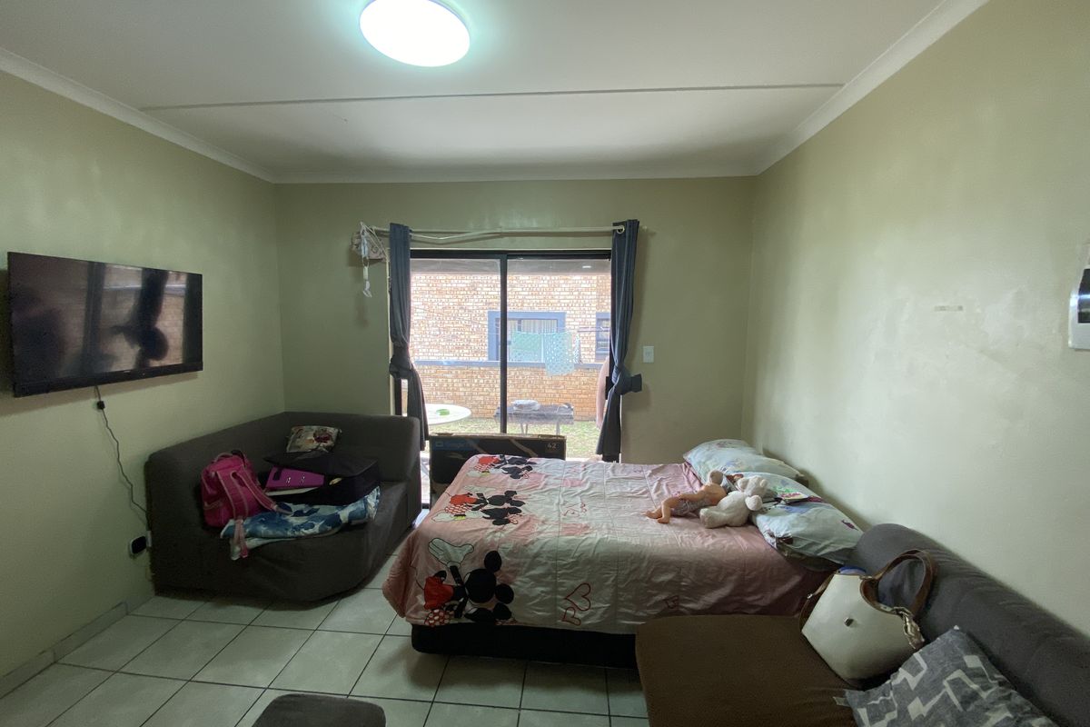 A bedroom featuring tiled flooring, a ceiling-mounted light fixture, and sliding glass doors providing access to the exterior.