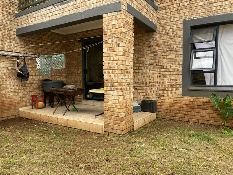 A covered patio area with brick pillars and tiled flooring, providing direct access to the garden and interior living space.