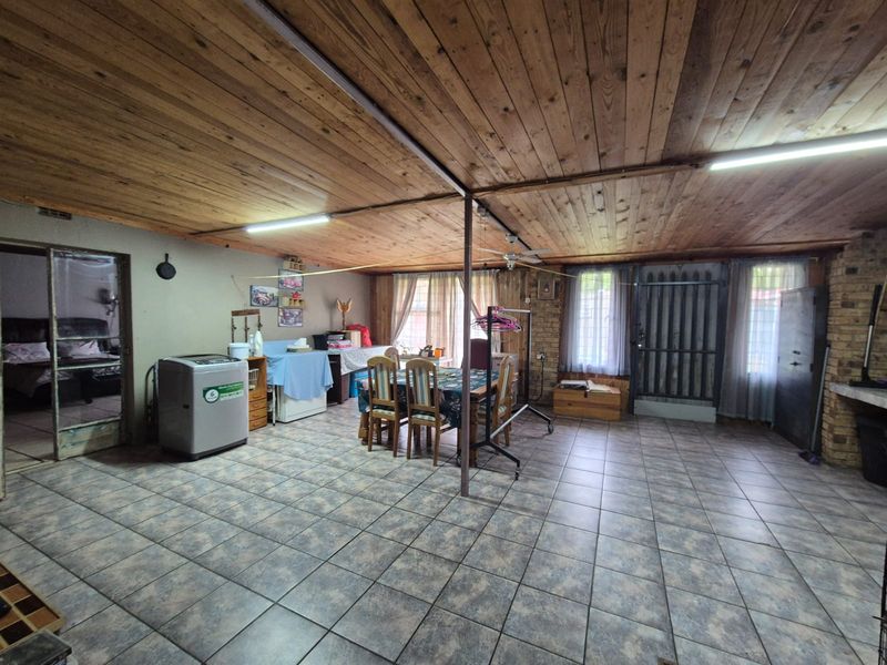 Spacious open-plan living area featuring exposed timber ceilings, ceramic tiled flooring, and exposed brick accents, offering a versatile layout for various living arrangements.