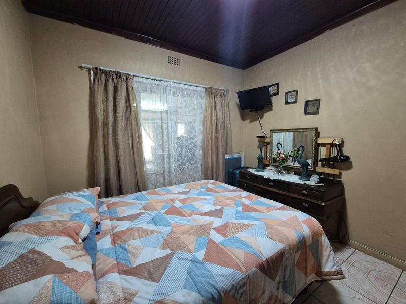 A bedroom featuring tiled flooring and a dark timber ceiling, offering a dated aesthetic that could be refreshed with modern finishes.