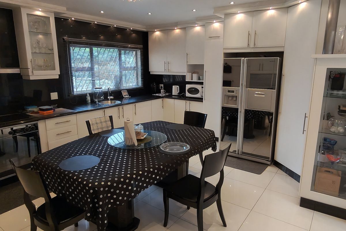 Modern kitchen featuring white cabinetry, black countertops, integrated appliances, and recessed lighting, providing a clean and functional culinary space.