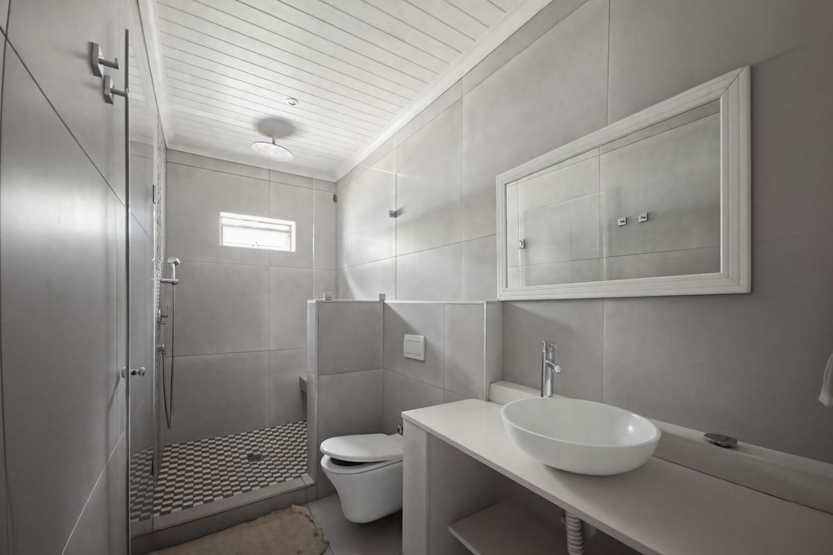 Modern bathroom featuring a walk-in shower with mosaic floor tiles, wall-mounted toilet, and a sleek vanity with a vessel sink.
