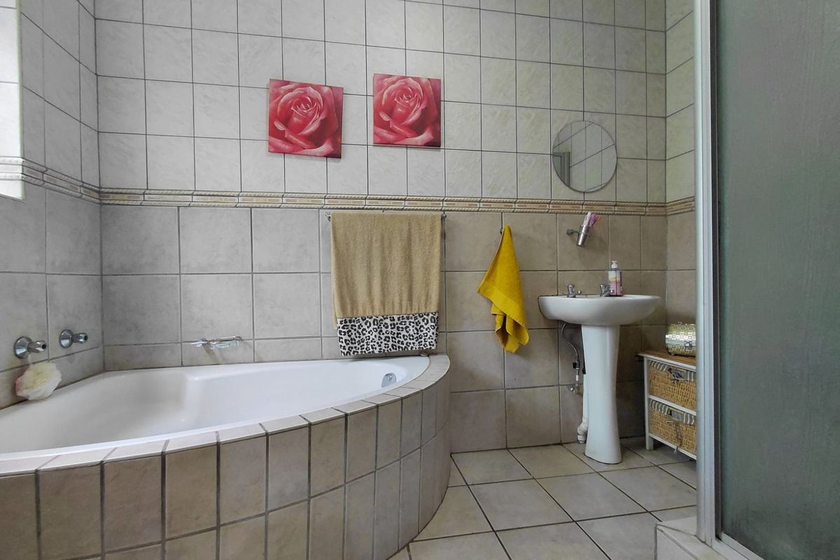 A functional bathroom featuring a corner bathtub, pedestal basin, and tiled finishes throughout.