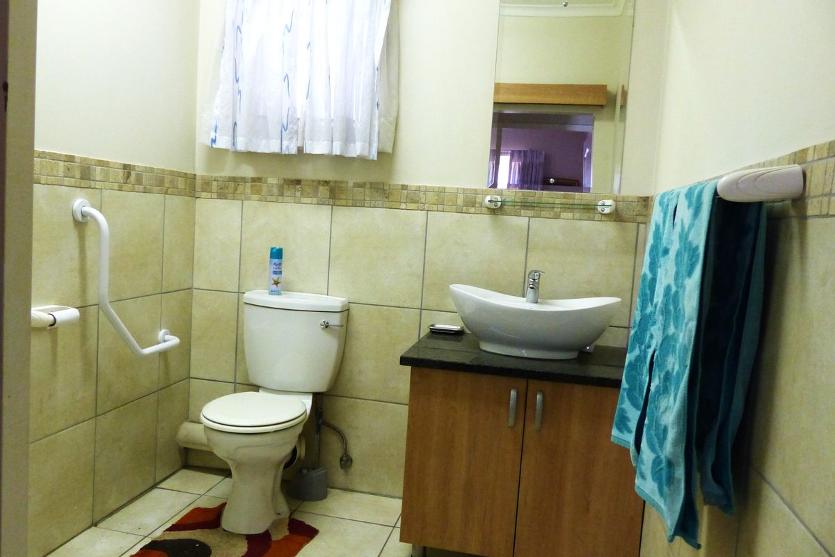 A functional bathroom featuring a vessel sink vanity, tiled walls with decorative border, and a wall-mounted safety grab rail.