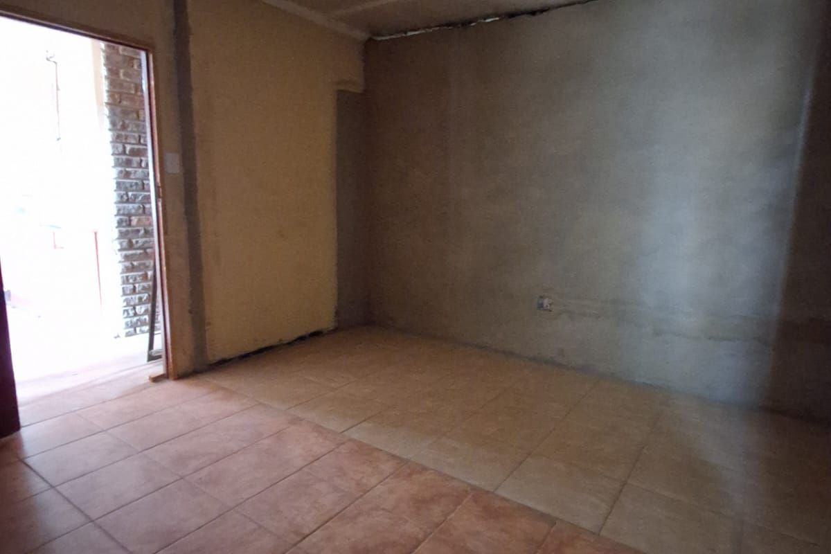 An unfinished interior room featuring tiled flooring and exposed wall surfaces, offering a blank canvas for renovation and custom finishing.